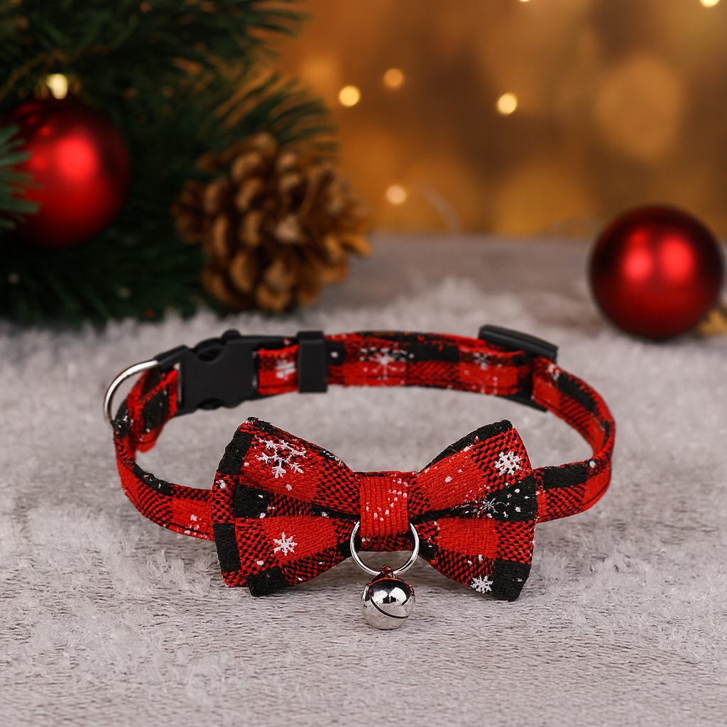 Red and black plaid dog collar with a bow tie and bell on a textured surface with Christmas decorations in the background.